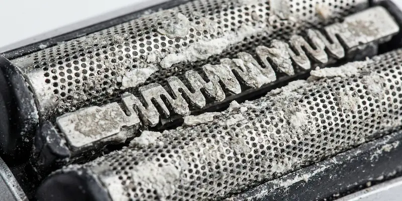 Hard water buildup on electric shaver foil — Close-up of white mineral residue on metal shaver components